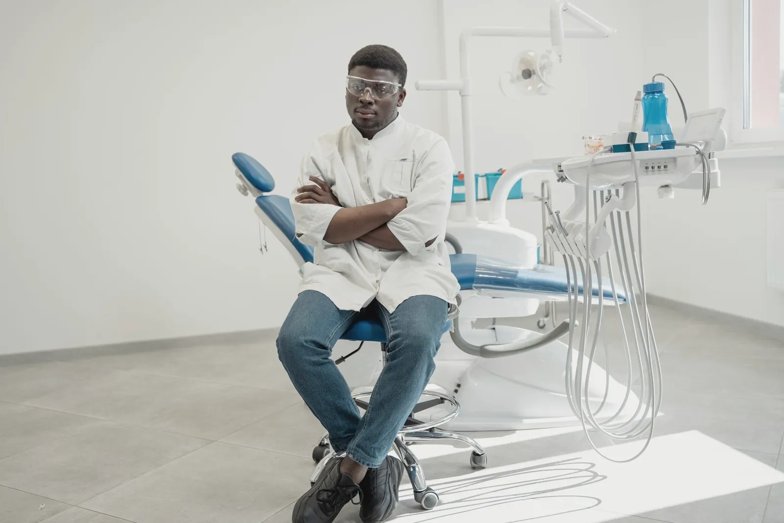 Dentista sentado junto a un sillón vacío, esperando pacientes